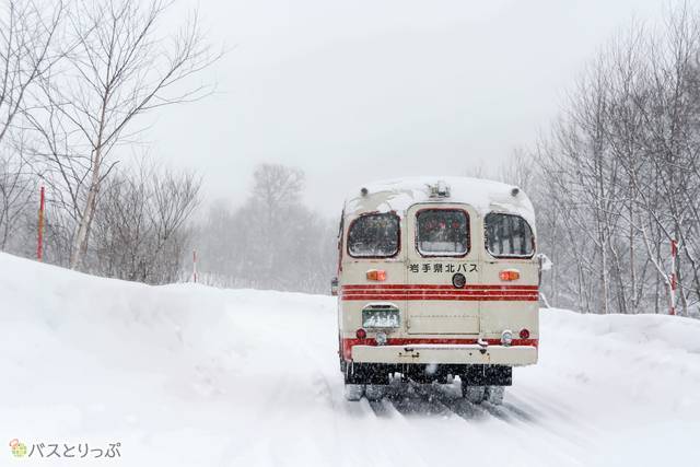 雪道を帰っていくバスを見送る