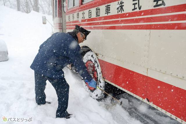 雪降りしきる中、車体にできたつららを叩き落とす古川さん